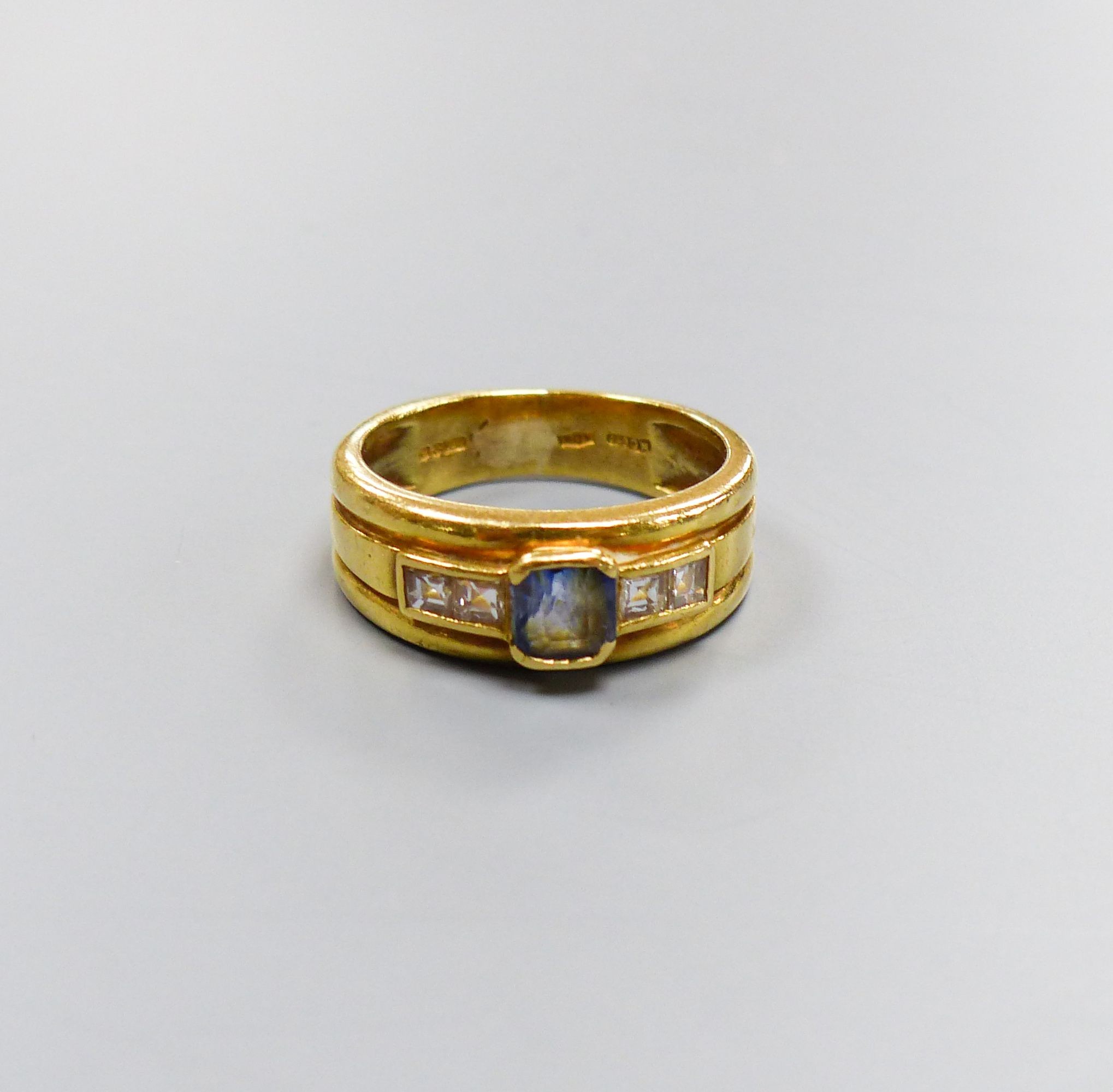 A modern 18ct gold, single stone sapphire and four stone diamond collet set dress ring, size M/N, gross 6.6 grams.